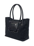 A black textured felt tote bag with smooth black leather handles, a front zippered pocket, and silver-tone studs, shown on a light gray background.