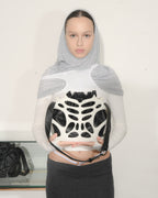 Person wearing a unique top with a black and white design, holding a similar item.