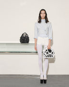 Woman holding a black and white handbag with a plain background