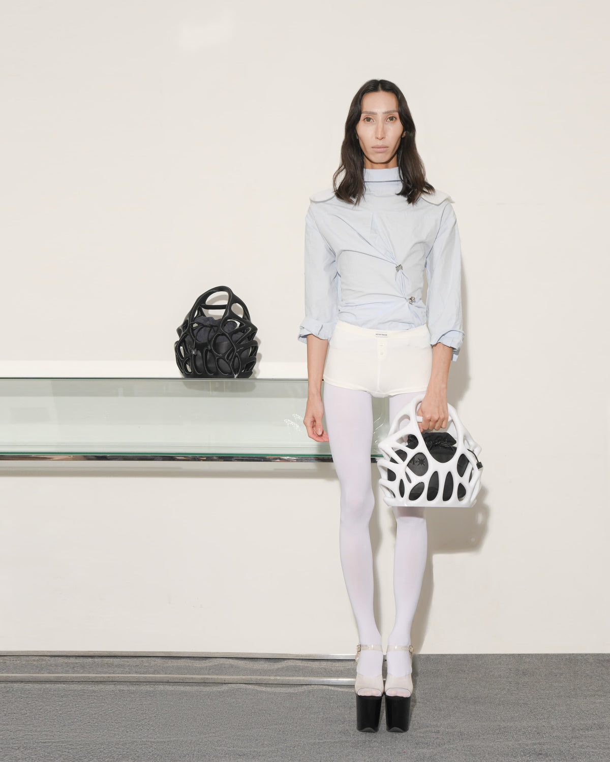 Woman holding a black and white handbag with a plain background