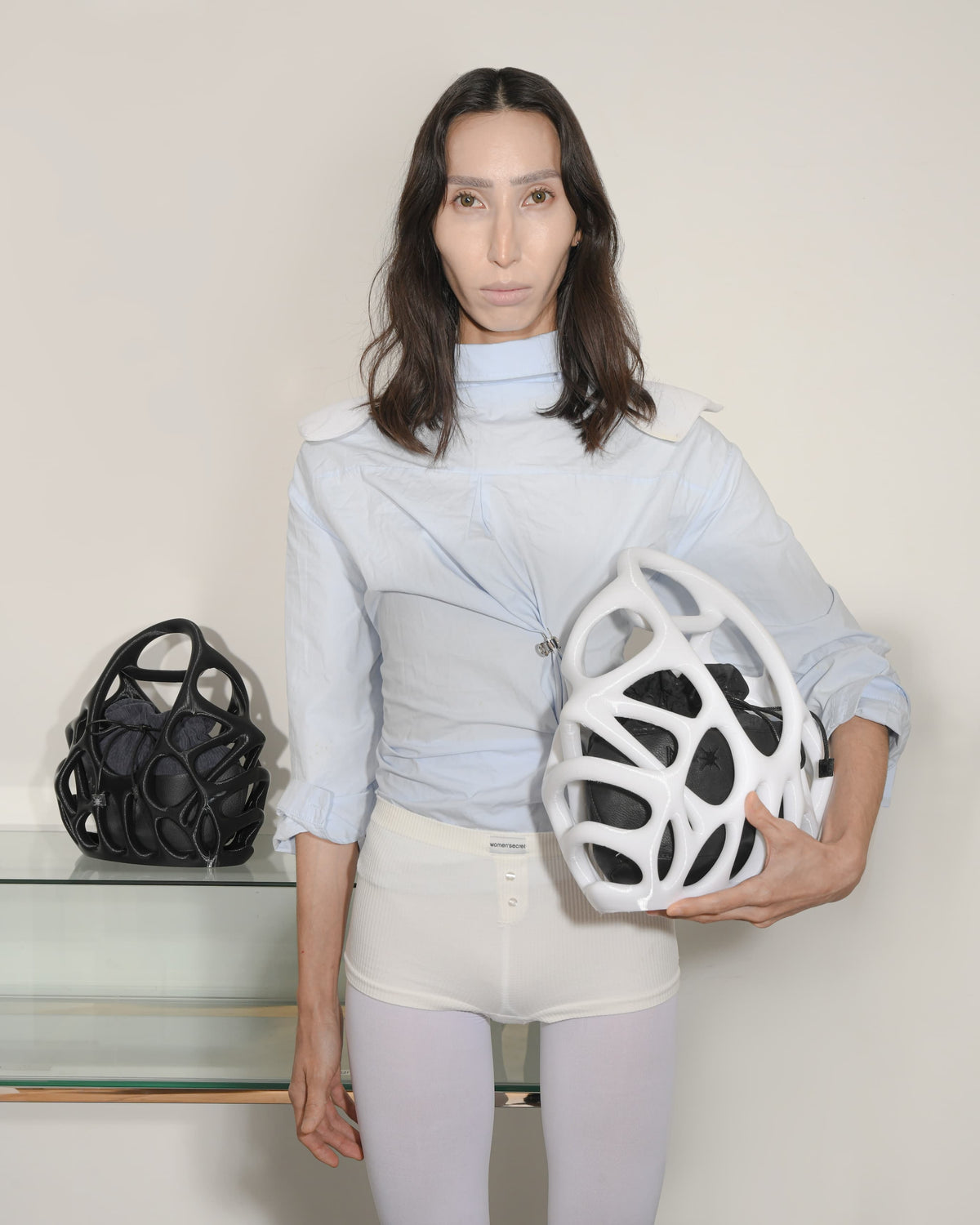 Person holding a white helmet and black bag against a plain background