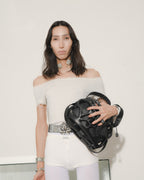 Woman holding a black handbag against a white background