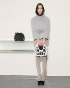 Woman holding a black and white handbag in a minimalistic setting
