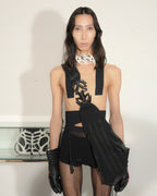 Model wearing a black outfit with cut-out design and gloves, standing against a plain background.
