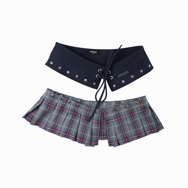 A navy suede belt with a detachable skirt featuring a plaid pattern. The belt has snap buttons for attachment, and the skirt is designed with a pleated style.